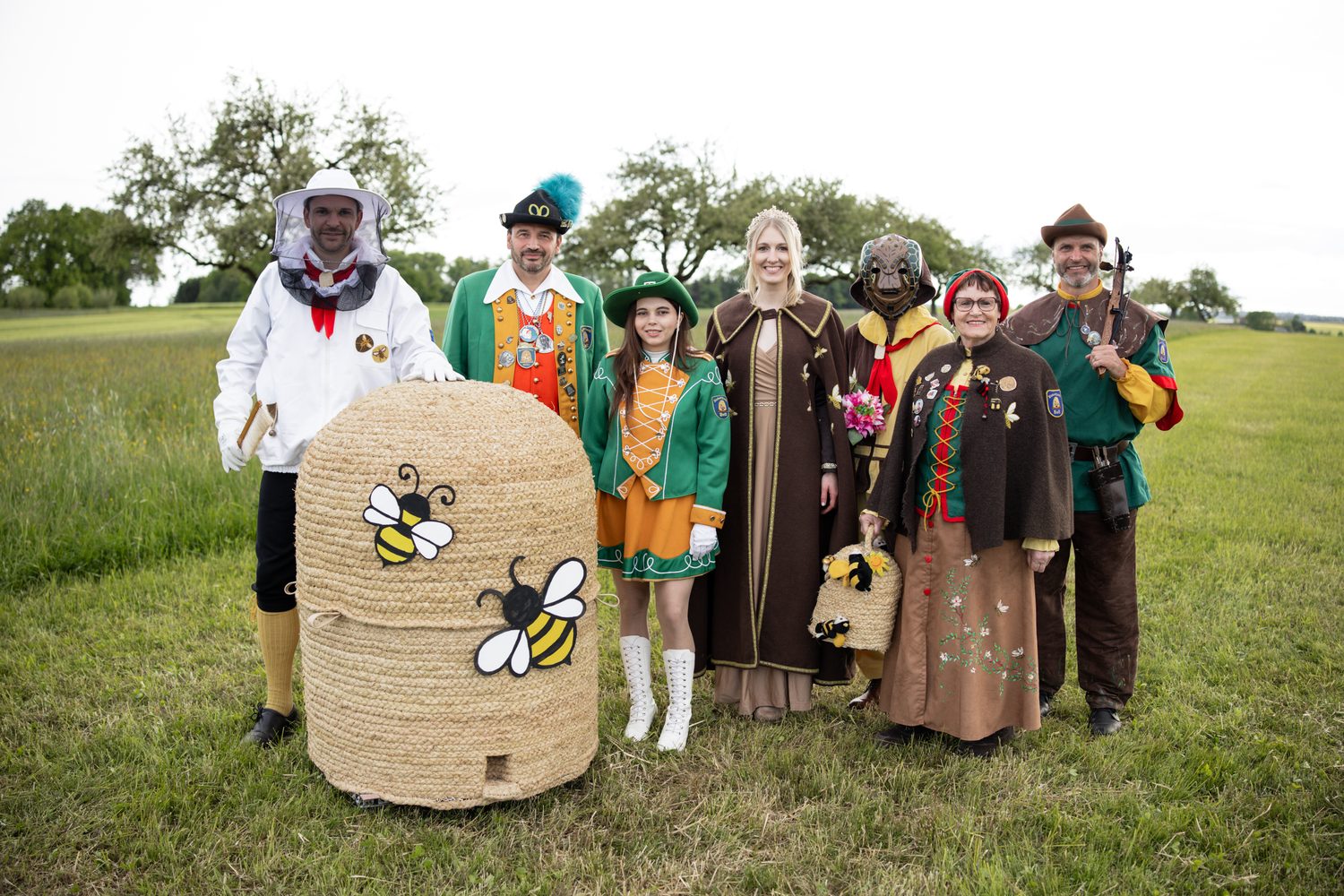 Die Figuren der Binkerzunft Boll nebeneinander vor einem Bienenkorb